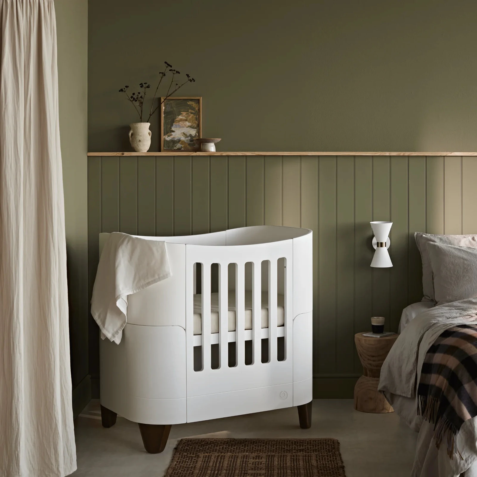Compact Serena Mini Cot with walnut-toned legs in a contemporary nursery.