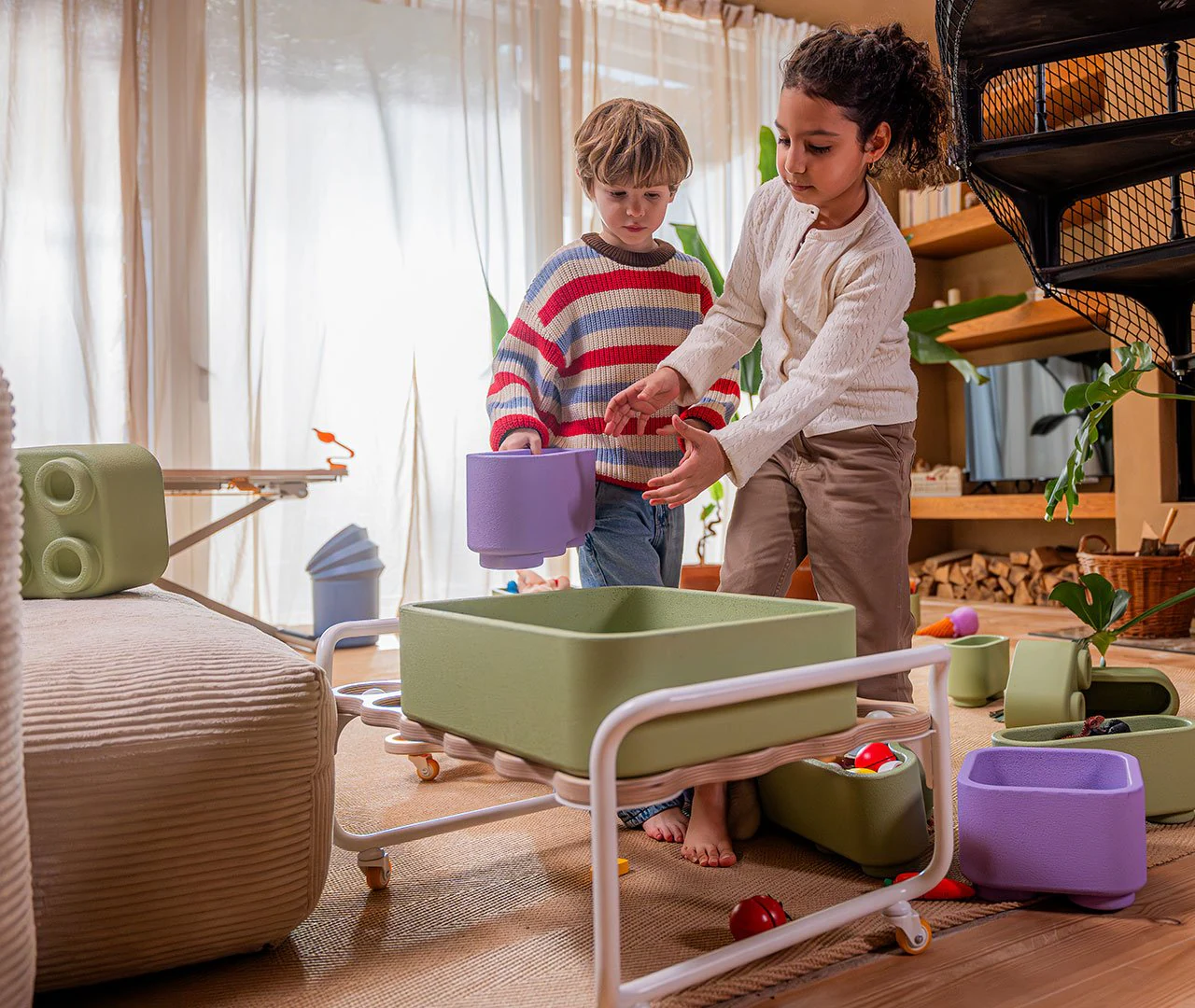Two children arranging lightweight containers around the poptop toy storage system