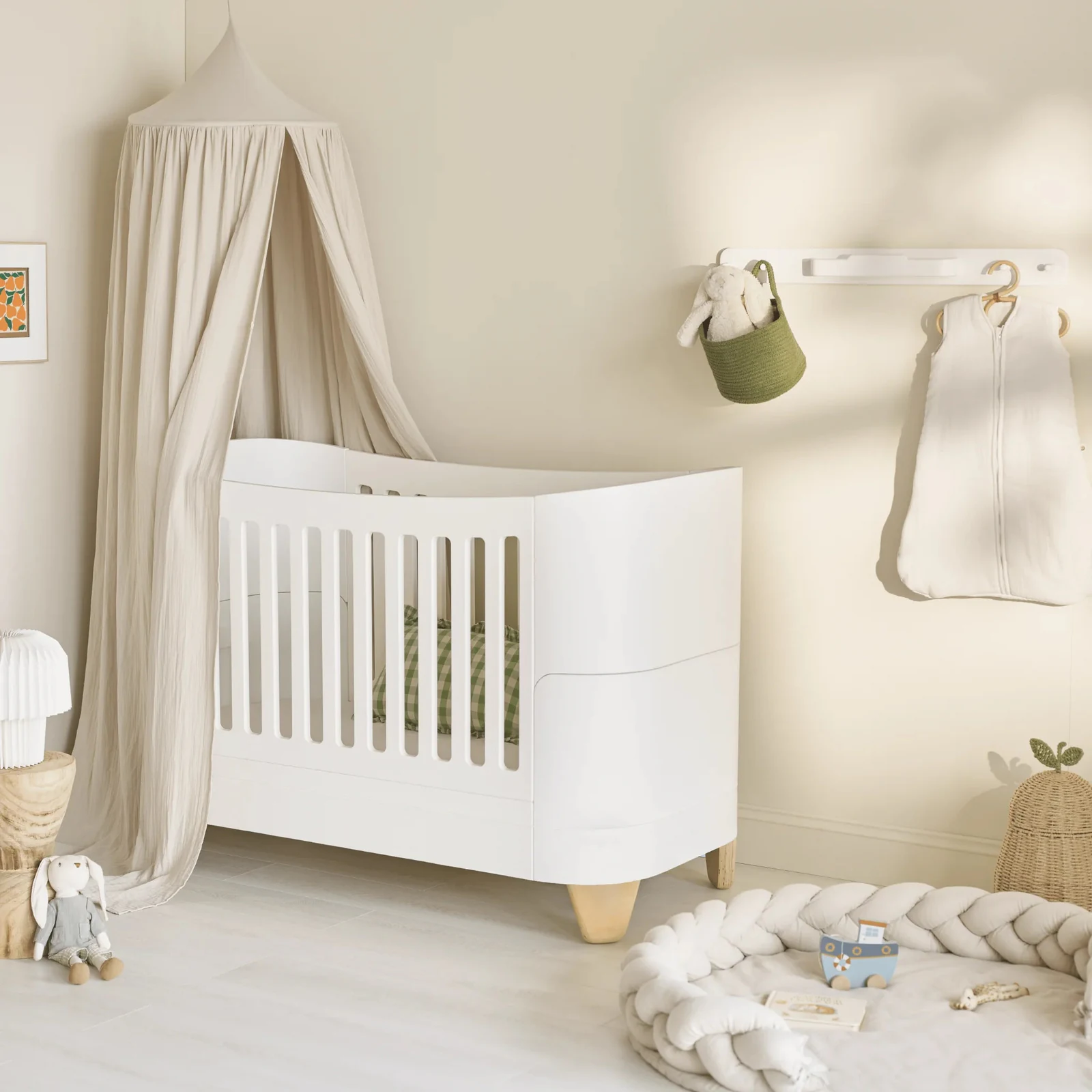 Serena Convertible Cot Bed with natural legs in a softly styled nursery beneath a muslin canopy.
